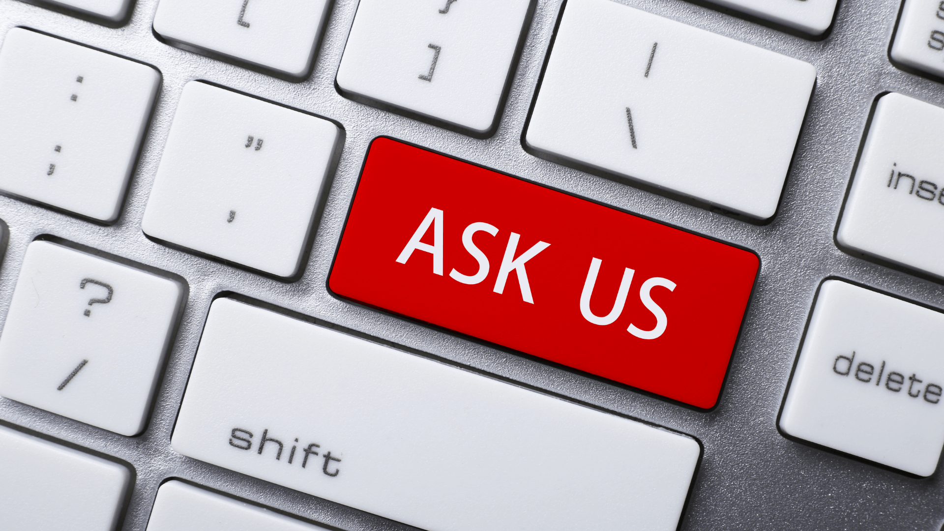 A partial image of a keyboard. There is a large red button that reads "Ask Us" in the center of the photo.