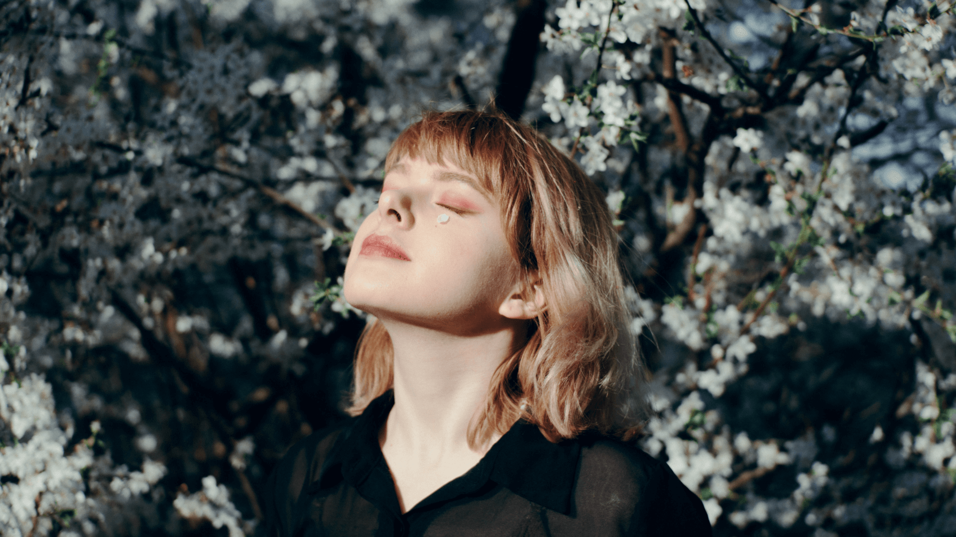 A woman, eyes closed, lifting her face to the sun