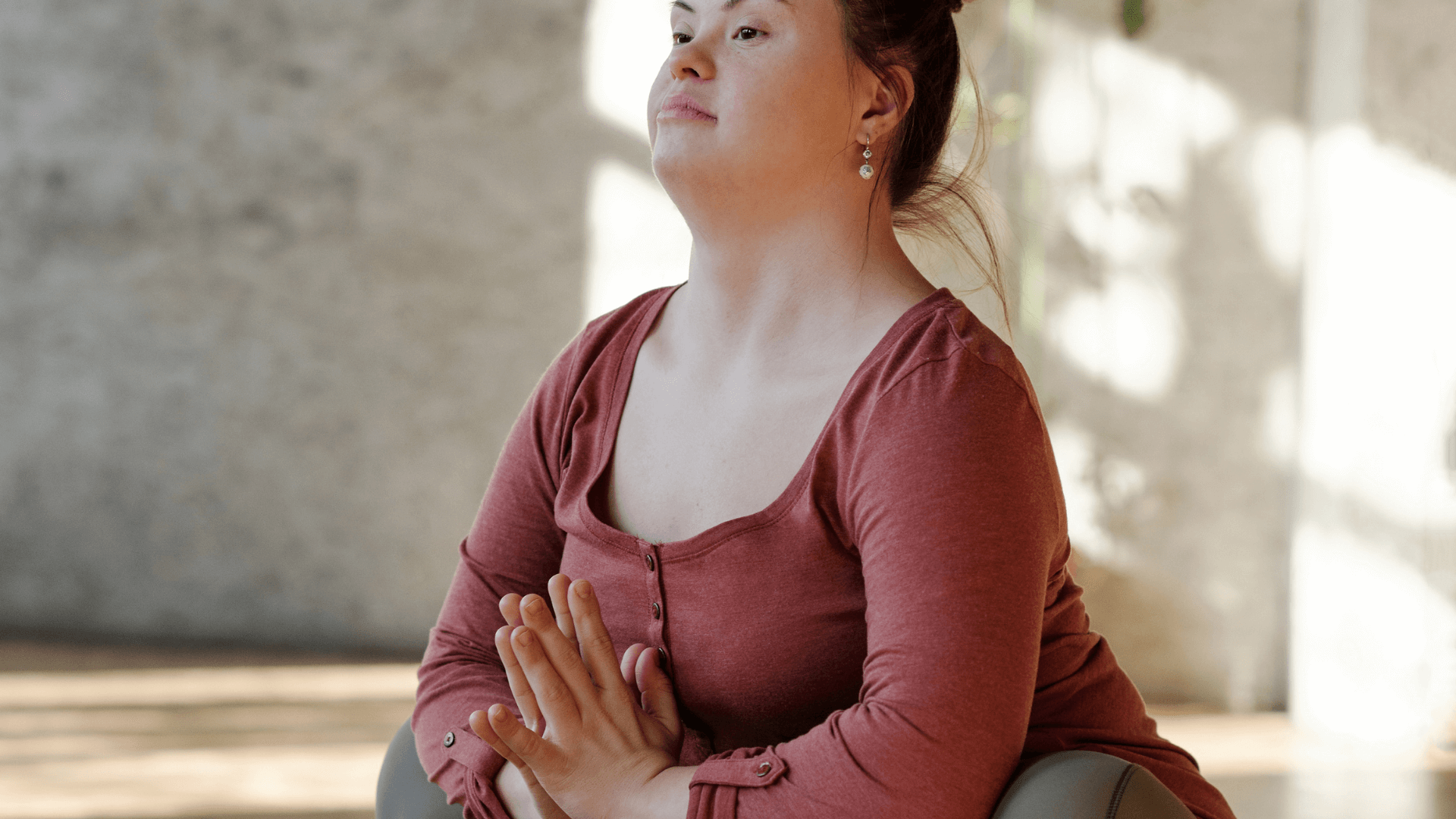 A woman in a squatting position, her hands are at heart center