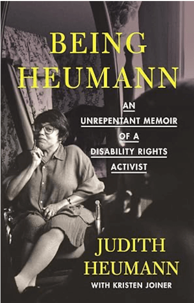 An image of Judith Heumann, a white woman in a manual wheelchair, her hand at her chin, looking at the camera. Text reading Being Heumann. An Unrepentant Memoir of a Disability Rights Activist. Judith Heumann with Kristen Joiner.